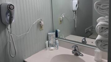 A bathroom with a white sink, a mirror, a hairdryer, and a towel rack.