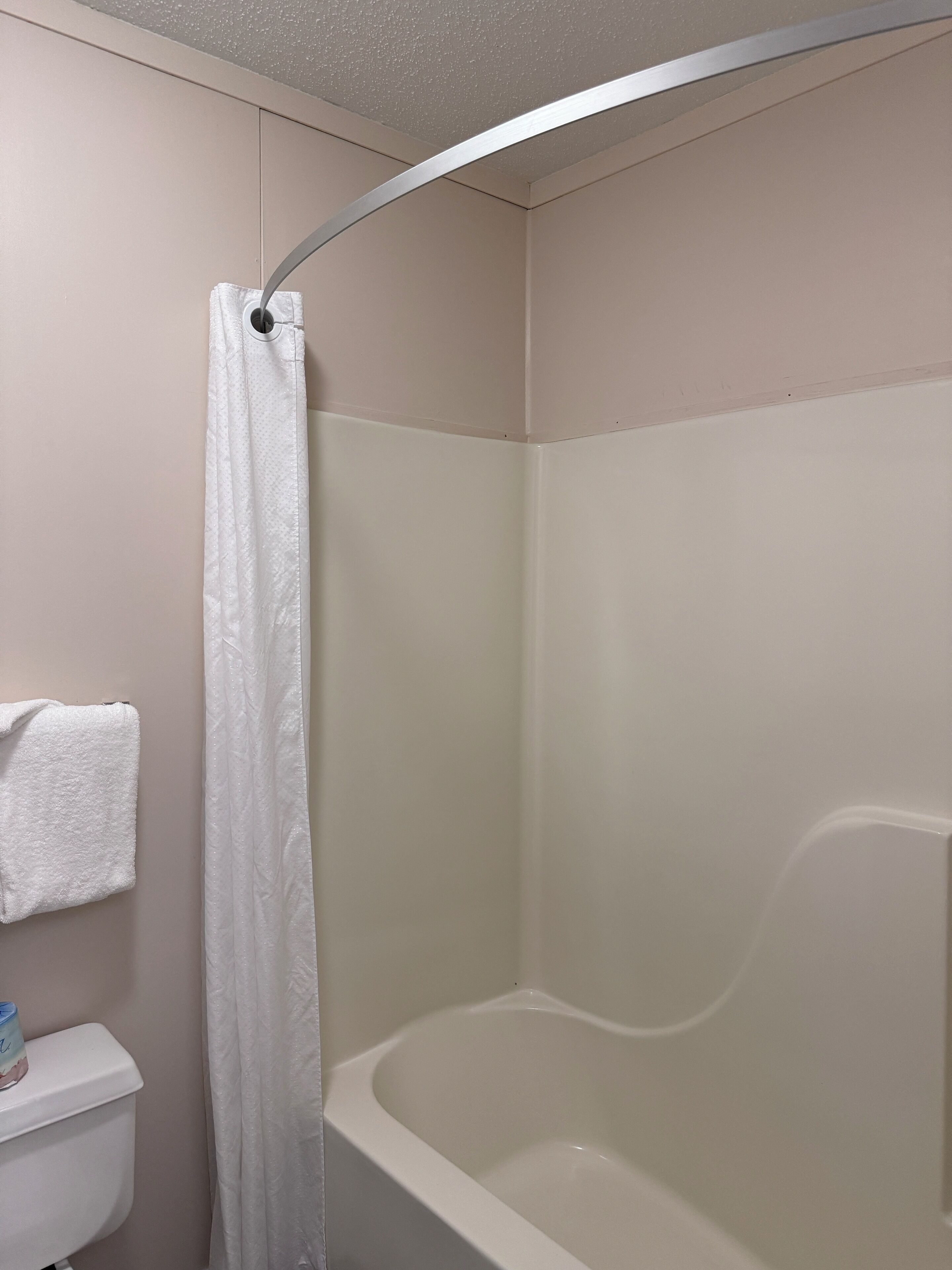 A bathroom with a shower, toilet, and towel rack.