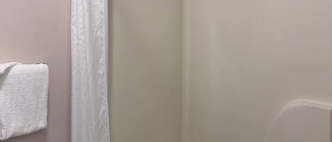 A bathroom with a shower, toilet, and towel rack.