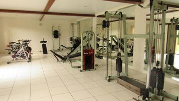 A gym with various exercise equipment, including a treadmill, weight machines, and a body-sculpt machine.