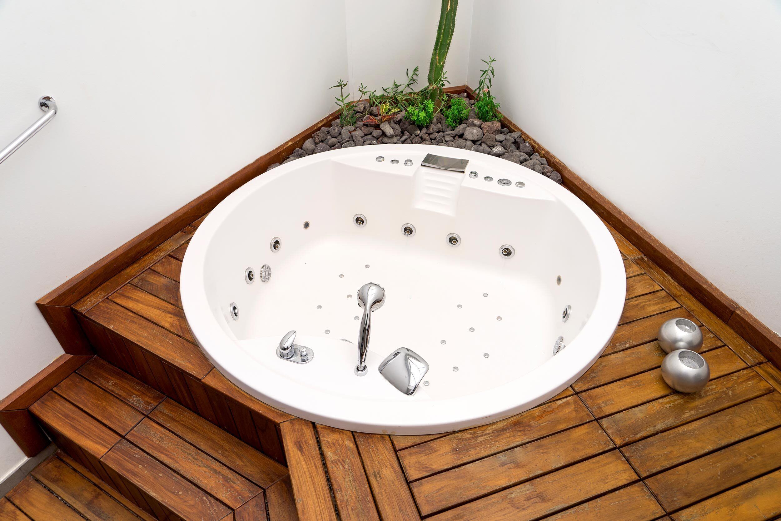 A modern bathroom with a freestanding bathtub, wooden steps, and a small plant arrangement.