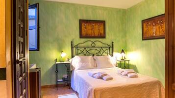 A bedroom with a bed, two nightstands, a window, and two wall-mounted paintings.