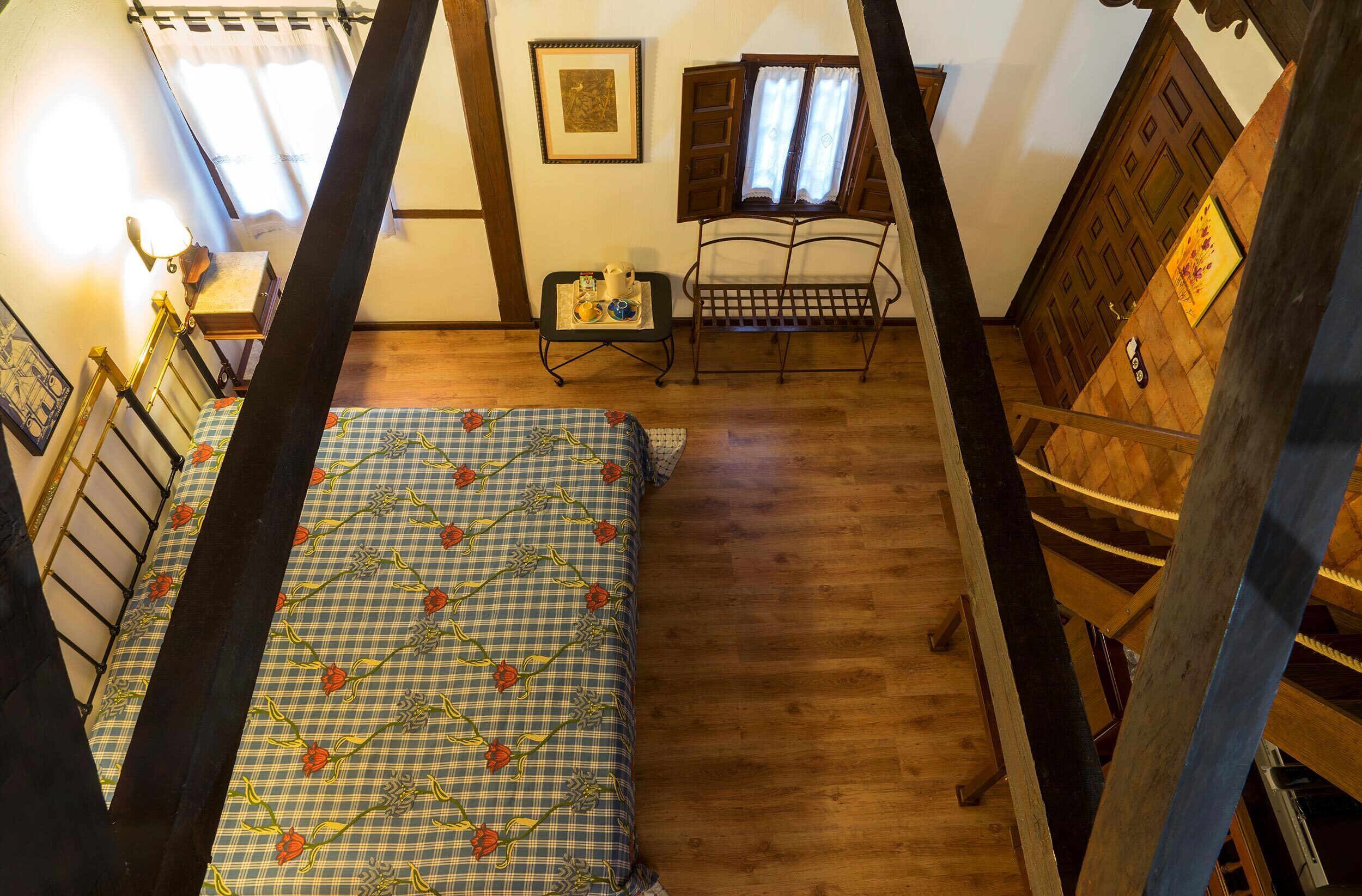 A bedroom with a bed, a small table with a lamp, a chair, and a wooden wardrobe.