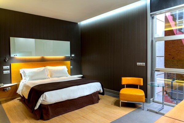 A modern hotel room with a large bed, a glass table, and a chair.