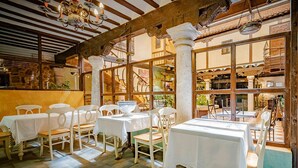 A restaurant with wooden beams, white tables, and chairs.