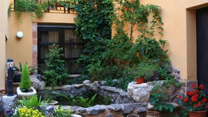 A courtyard with a stone wall, potted plants, and a small water feature.
