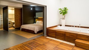 A modern bathroom with a large bathtub, wooden vanity, and a potted plant.