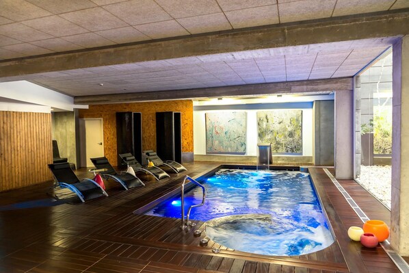 A spa area with a hot tub, lounge chairs, and a wooden floor.