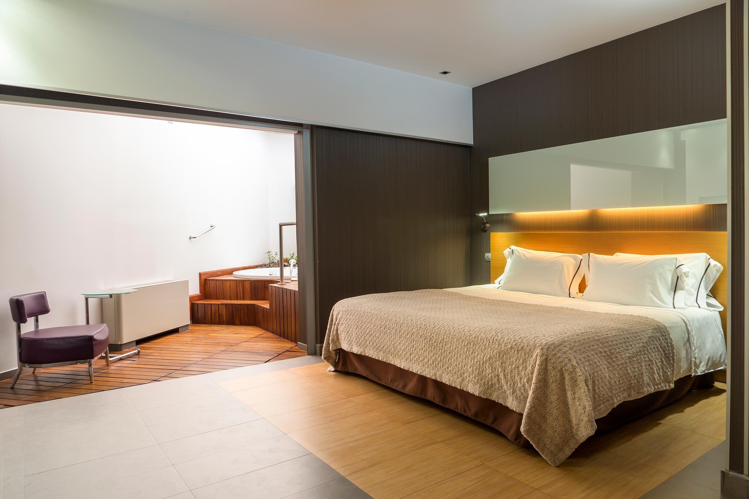A modern hotel room with a large bed, a desk, and a chair.