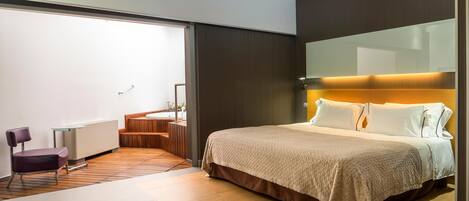 A modern hotel room with a large bed, a desk, and a chair.