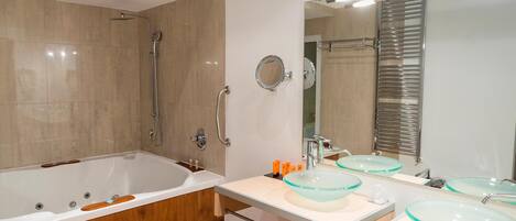 Un baño moderno con una bañera independiente, dos lavamanos de cristal, un espejo grande y una zona de ducha.