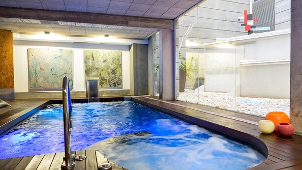 A hot tub area with wooden flooring, a metal railing, and abstract art on the walls.