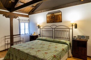 Quarto com cama, mesa de cabeceira, luminária, quadro e janela com cortinas.