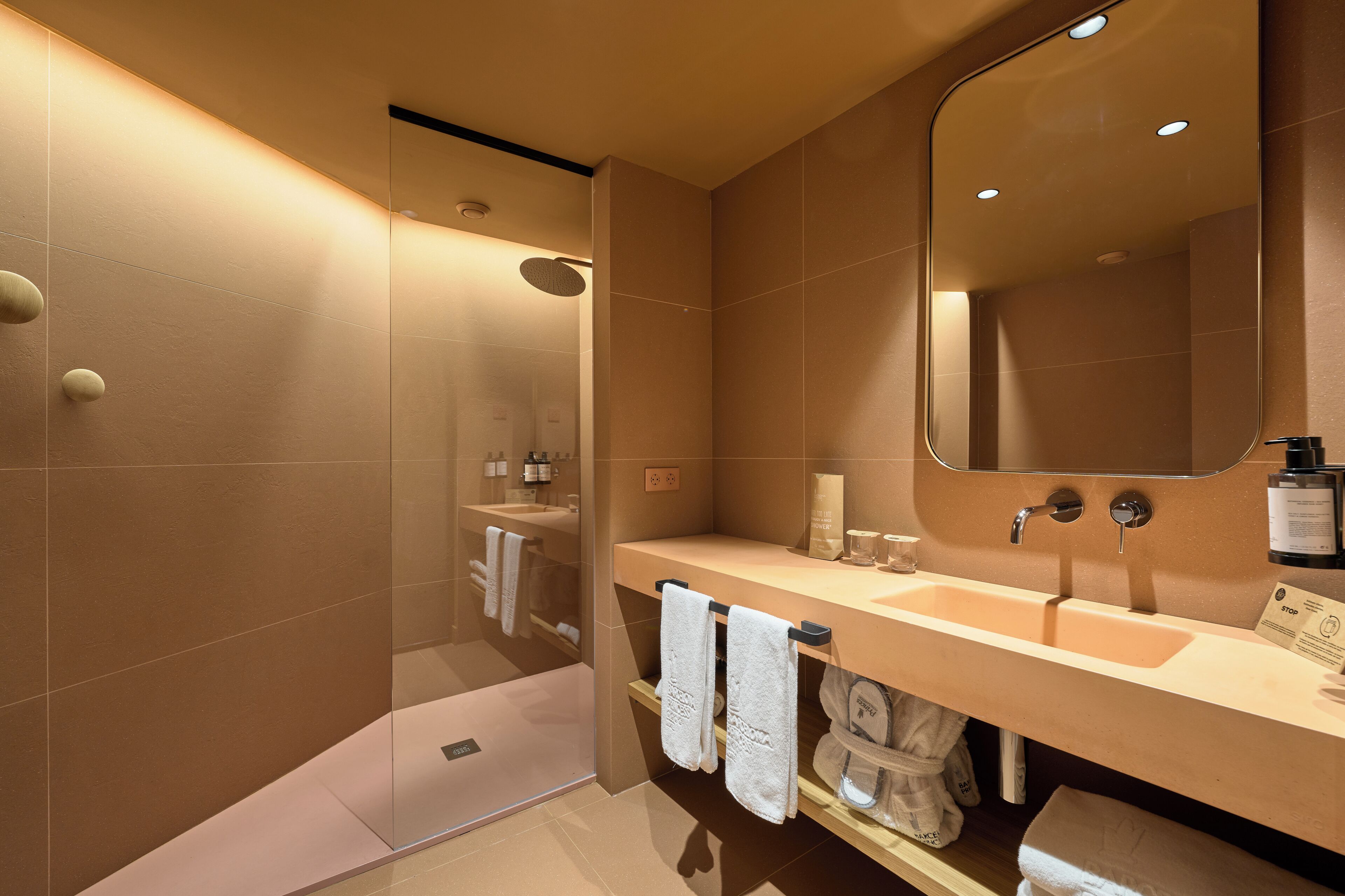 A modern bathroom with a large mirror, two sinks, and a shower area.
