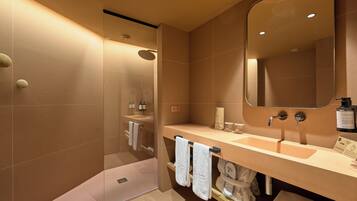 A modern bathroom with a large mirror, two sinks, and a shower area.