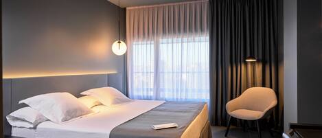 Una habitación de hotel moderna con una cama bien hecha, una silla y un piano.