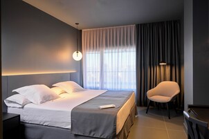 A modern hotel room with a neatly made bed, a chair, and a piano.