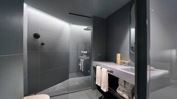 Un bagno moderno con doccia vetrata, un water bianco, un mobile lavabo con specchio e un lavandino.