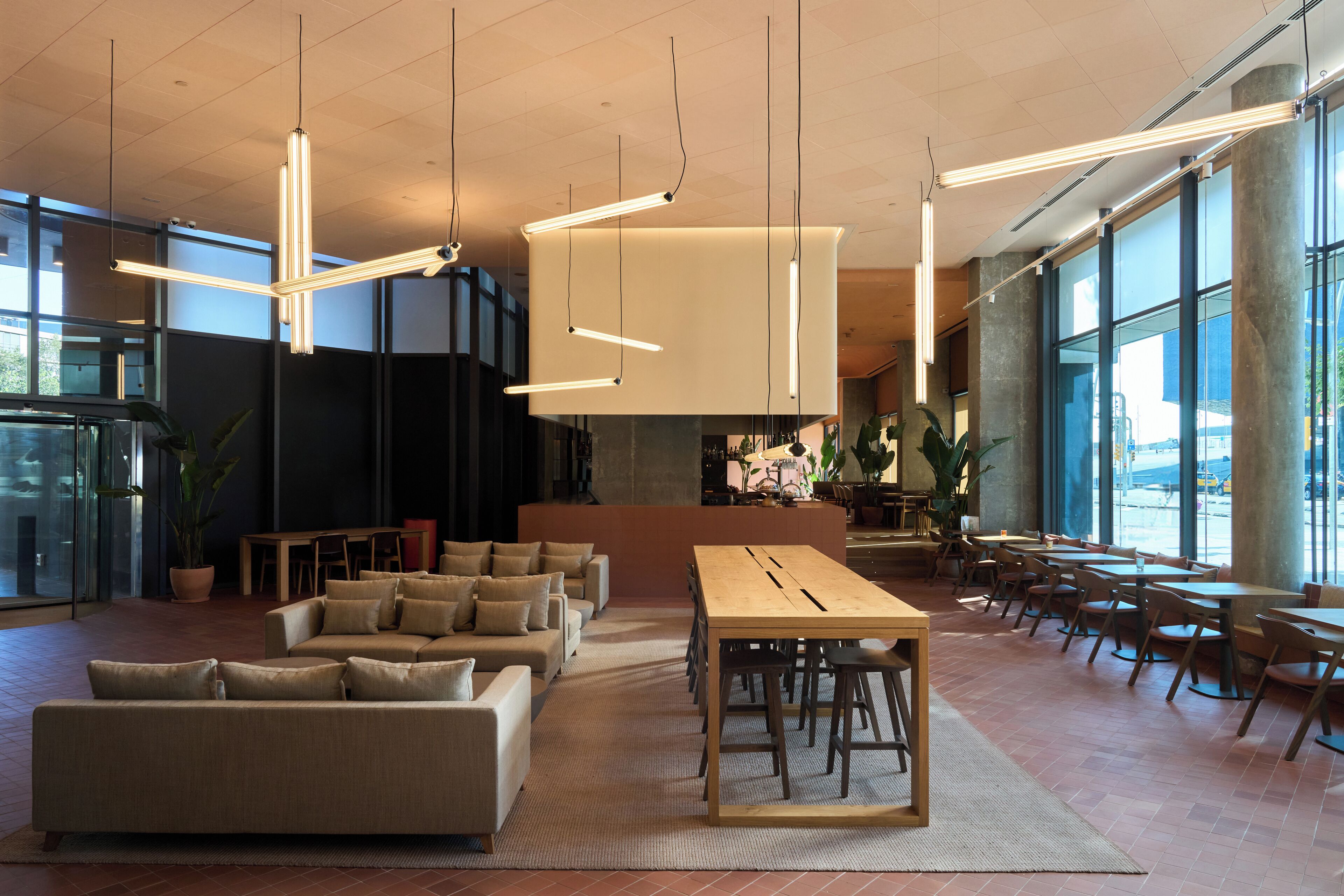 Un hall d’entrée spacieux avec un grand espace salon, une longue table et des lampes suspendues.