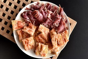 A plate of cured meats and cheese on a wooden board.