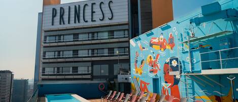 A pool area with lounge chairs and a building labeled 'PRINCESS' in the background.