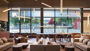 A modern interior with seating arrangements, large windows, and hanging lights. - Hotel Barcelona Princess (Barcelona)