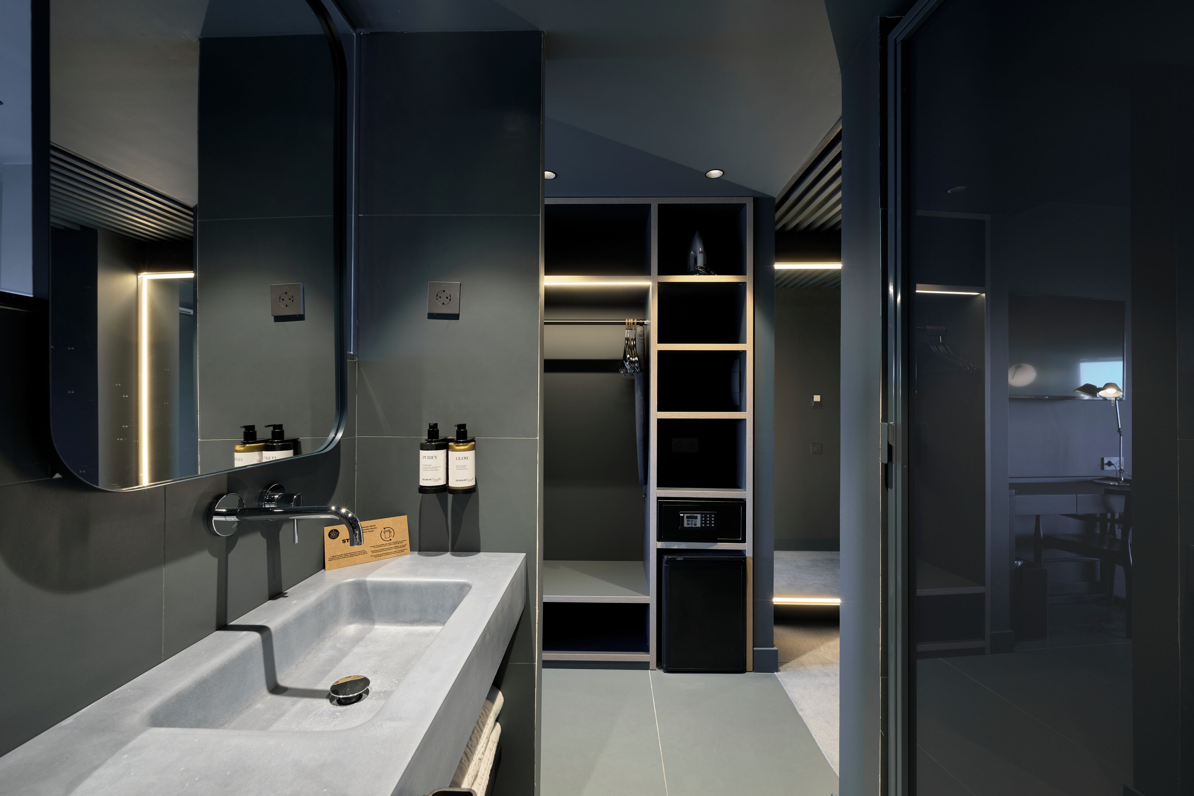 Un baño moderno con un lavamanos grande, espejo y estanterías integradas.