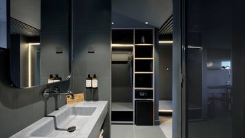 Un baño moderno con un lavamanos grande, espejo y estanterías integradas.