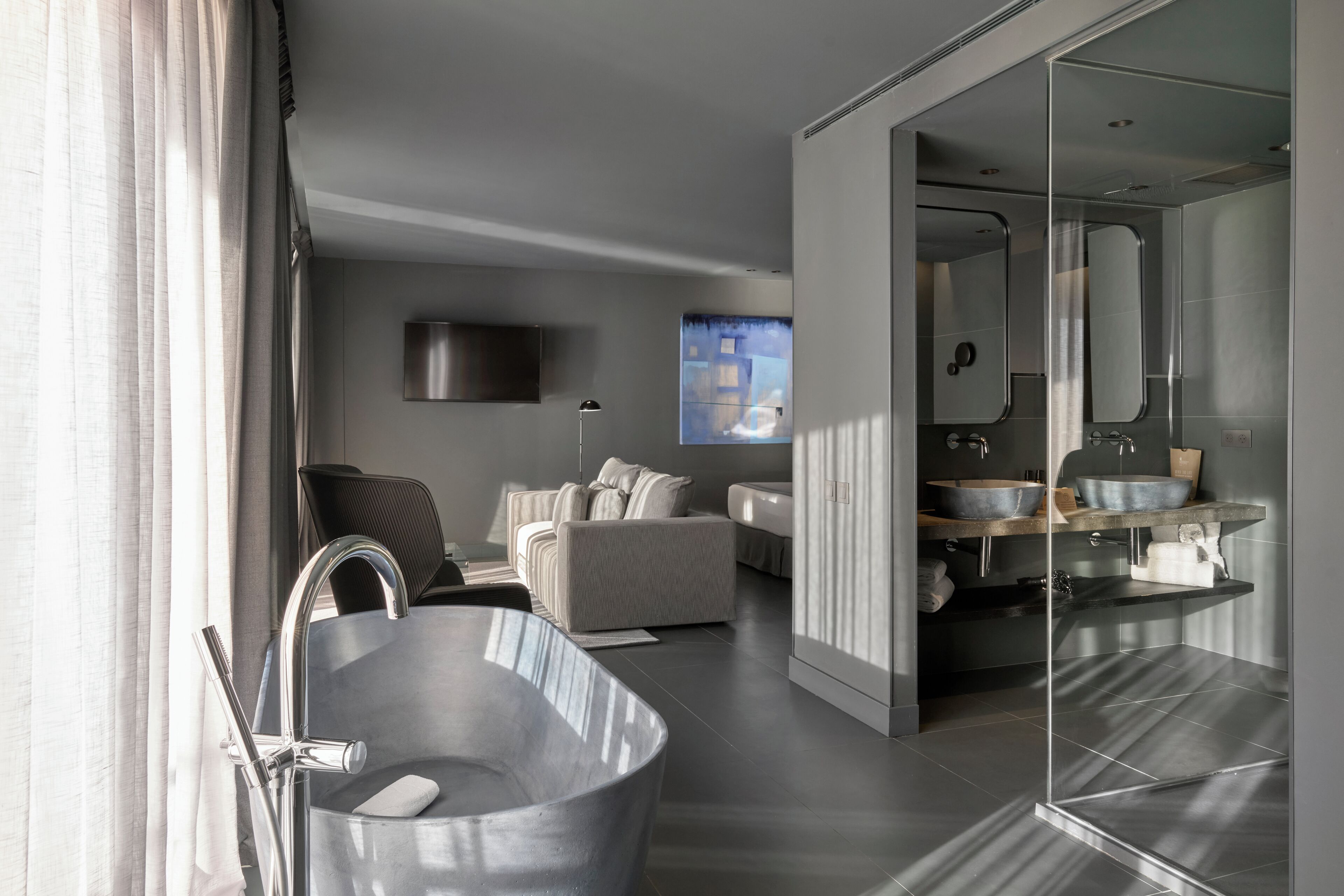Een moderne badkamer met een vrijstaand bad, een grote spiegel en een strak badkamermeubel.