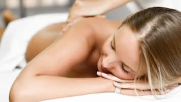 A person lying on a massage table receiving a back massage.