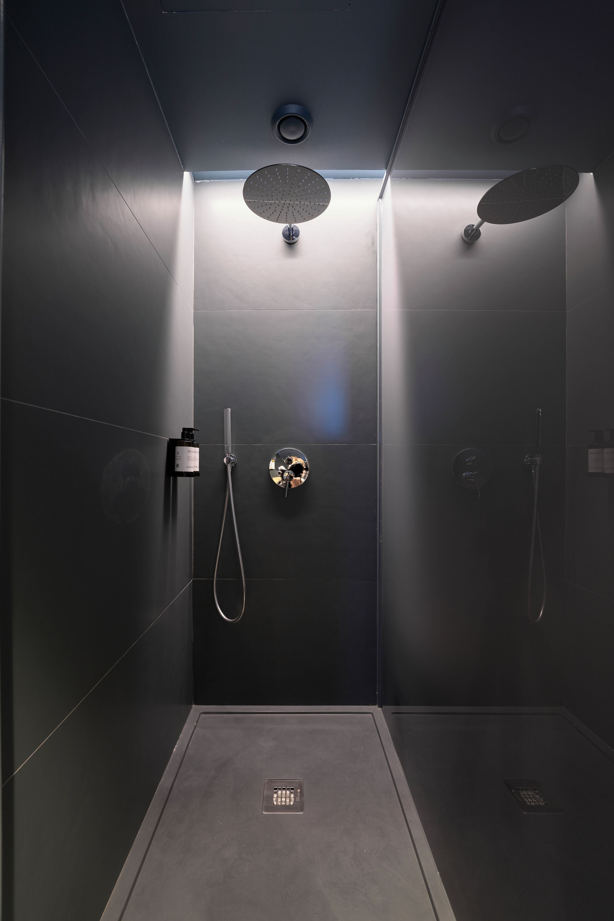 Ducha moderna con panel de control, cabezal de ducha de mano y rociador circular empotrado.