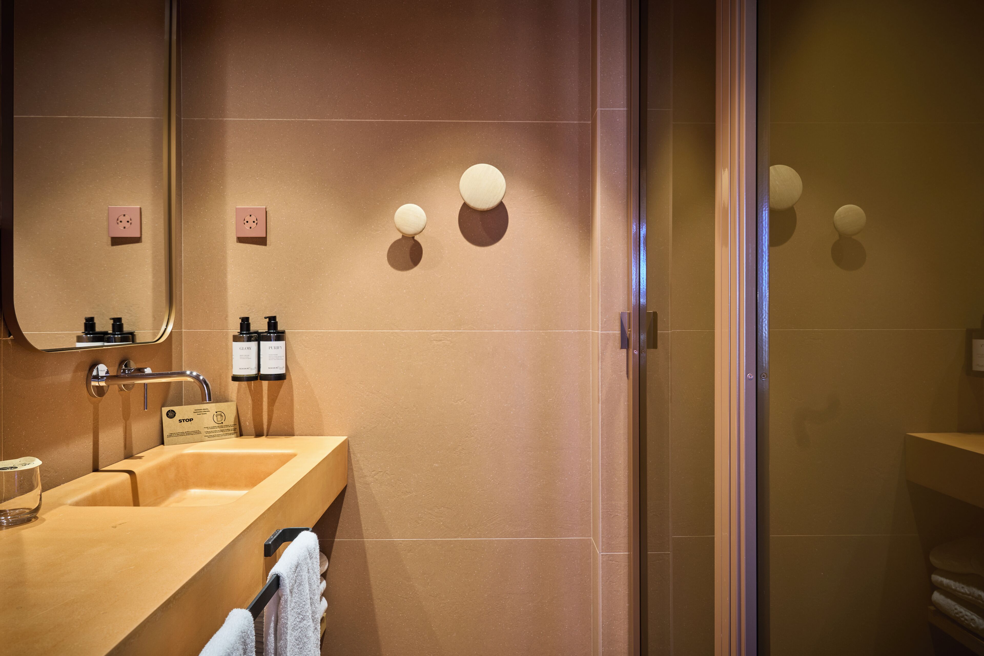 Een moderne badkamer met een beige wastafel, spiegel en twee ronde wandlampen.