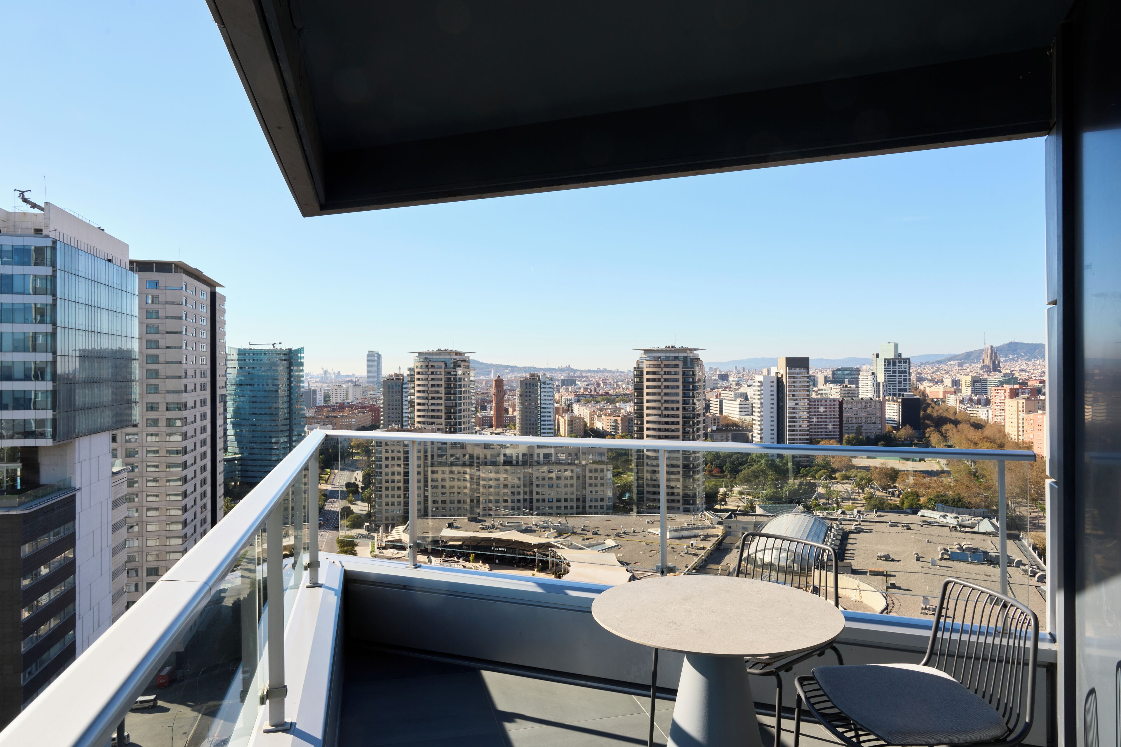 Un balcón con una mesa y sillas, con vistas a la ciudad.