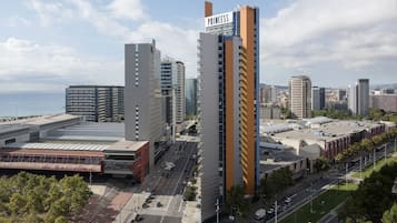 Un hotel de gran altura con un llamativo letrero 'PRINCESS', rodeado de otros edificios y vistas al mar.