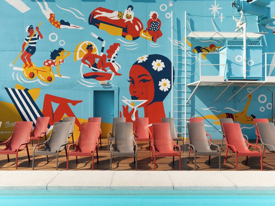 A poolside area with lounge chairs and a mural depicting various leisure activities.