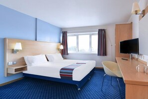 A hotel room with a bed, a desk, a chair, a television, and a window with curtains. - Travelodge Worcester (Worcester)