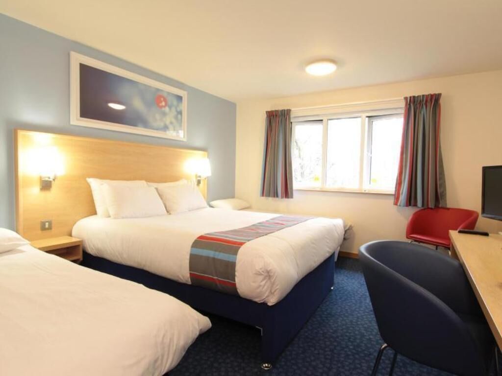 Ein Hotelzimmer mit einem großen Bett, Nachttischen, einem Schreibtisch und einem Sessel.