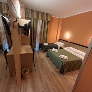 A hotel room with two beds, a desk with a chair, a television, and a small trash bin. - Hotel Lugano (Milan)