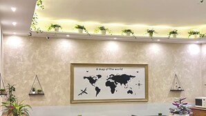 Et hotel lobby med et verdenskort på væggen, borde og stole samt potteplanter.