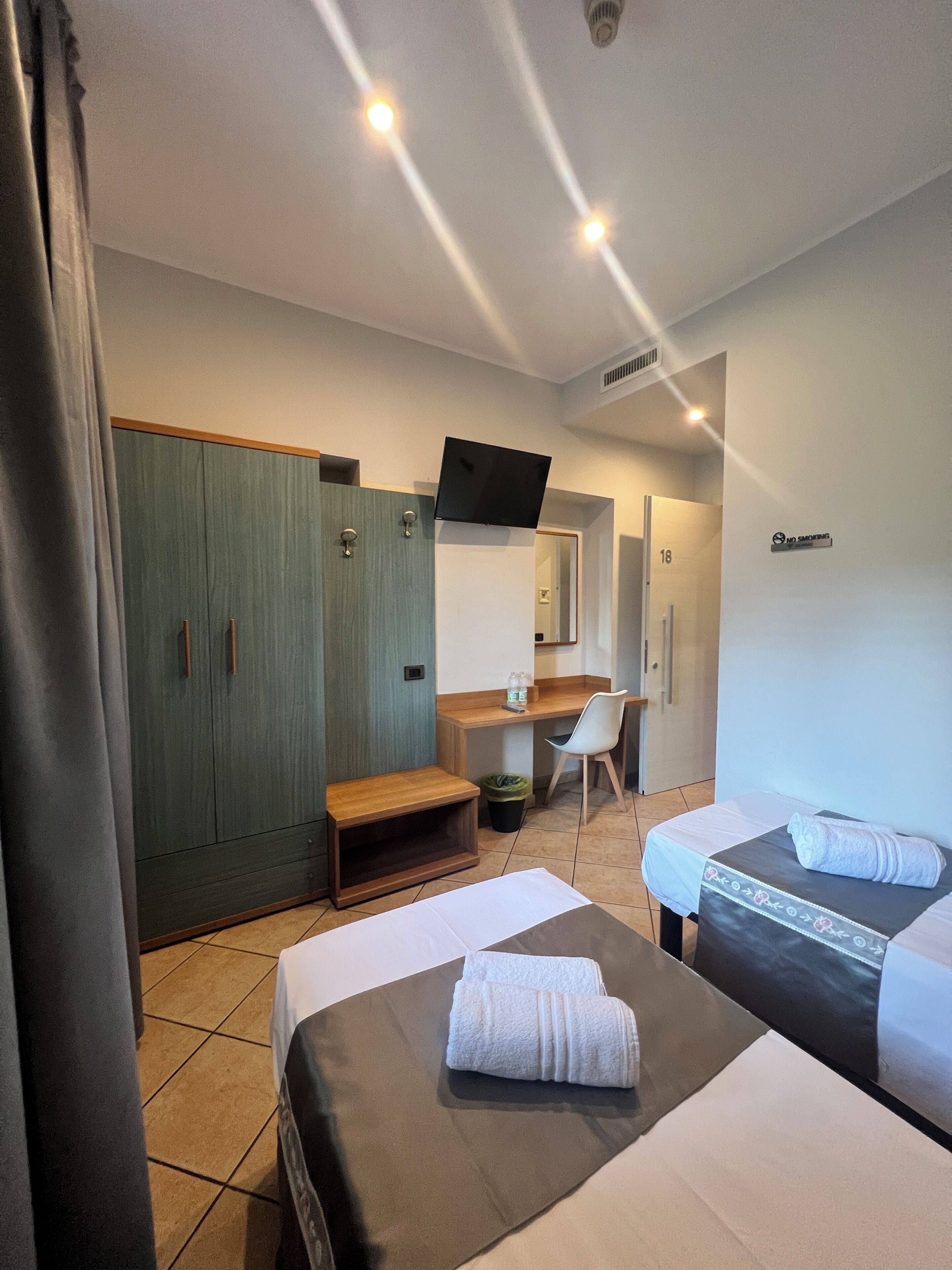 Une chambre d’hôtel avec deux lits, un bureau, une chaise, une armoire et un téléviseur.