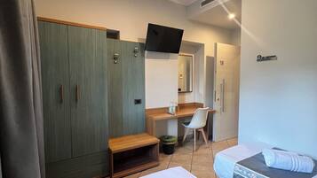 A hotel room with two beds, a desk, a chair, a wardrobe, and a TV.