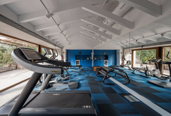 Un gimnasio con cintas de correr, elípticas y estaciones de pesas.