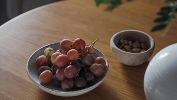Una mesa de madera redonda con un cuenco de uvas y un tazón pequeño de granos de café.