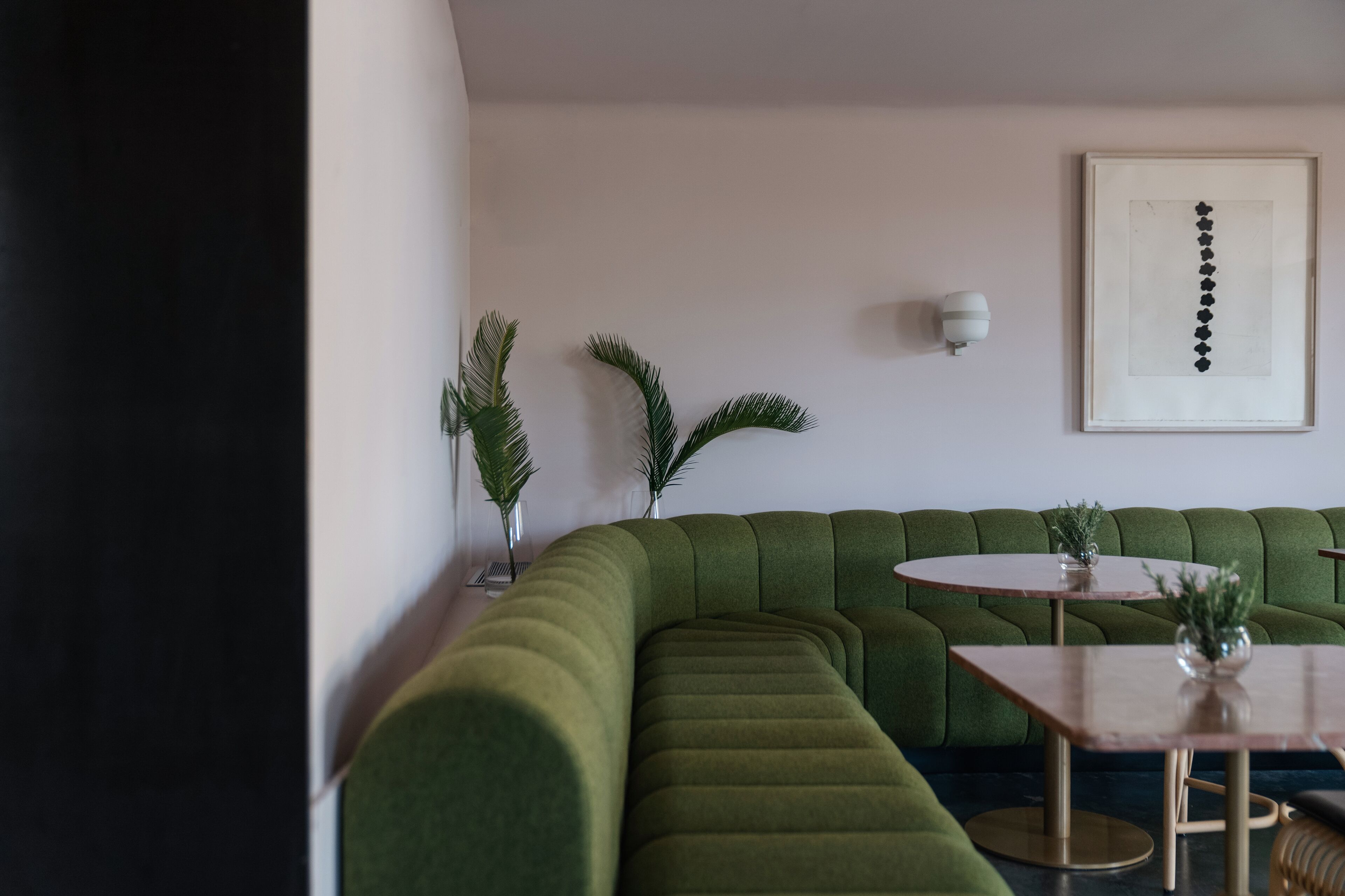Ein modernes Wohnzimmer mit einem grünen Ecksofa, einem runden Couchtisch und einem gerahmten abstrakten Kunstwerk an der Wand.
