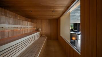 A wooden interior with a bench and a window overlooking an outdoor area.