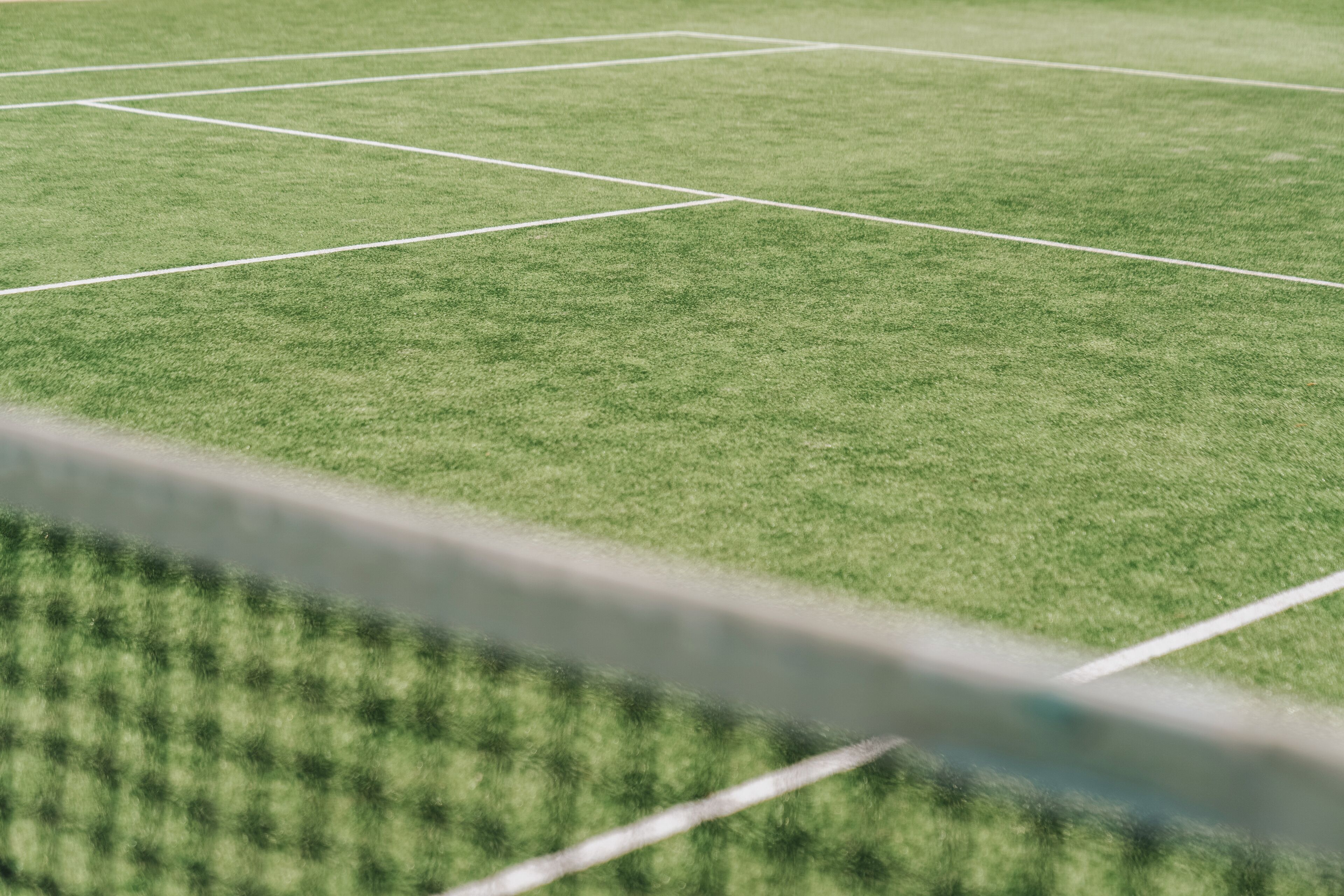 Primer plano de un campo deportivo verde con líneas blancas delimitadoras.