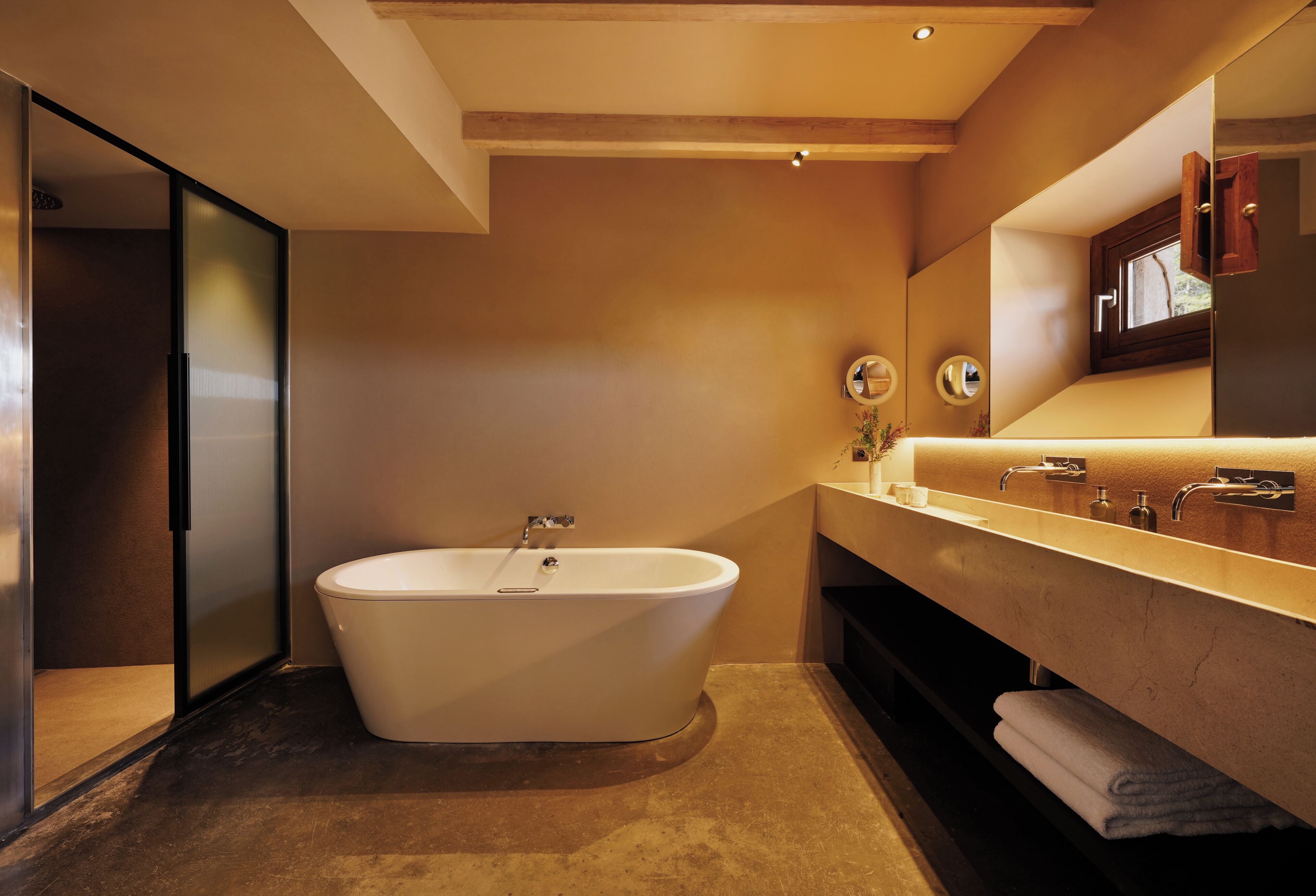 Un baño moderno con una bañera independiente, un espejo grande y un tocador con lavamanos.