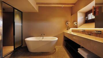 Un baño moderno con una bañera independiente, un espejo grande y un tocador con lavamanos.