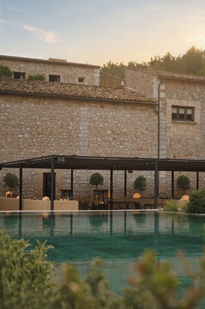 A stone building with a pool in front.
