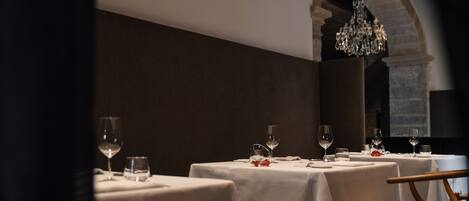 A dining area with tables set for two, each with a wine glass and a water glass.